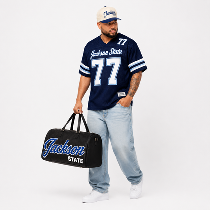 Jackson State Legacy Campus Collection male campaign model in navy jersey with cap and travel bag